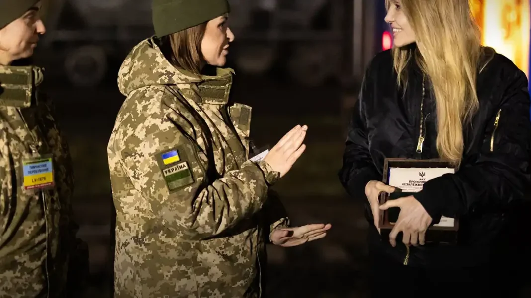 Авточернетка - Modista - Жіночий журнал Анджеліна Джолі посміхається поруч із двома військовослужбовцями Державної прикордонної служби України, тримаючи в руках подаровану національну символіку та коїн ДПСУ